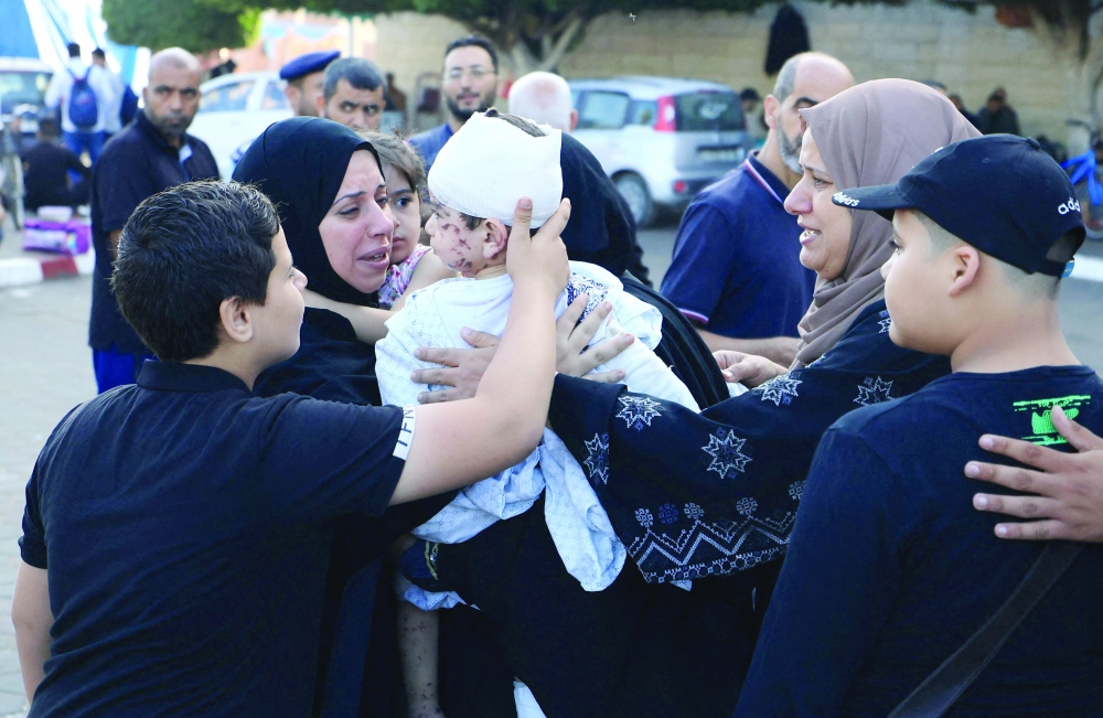 A woman holds an injured toddler following the Israeli bombardment of Deir Balah in the central Gaza Strip. — AFP 