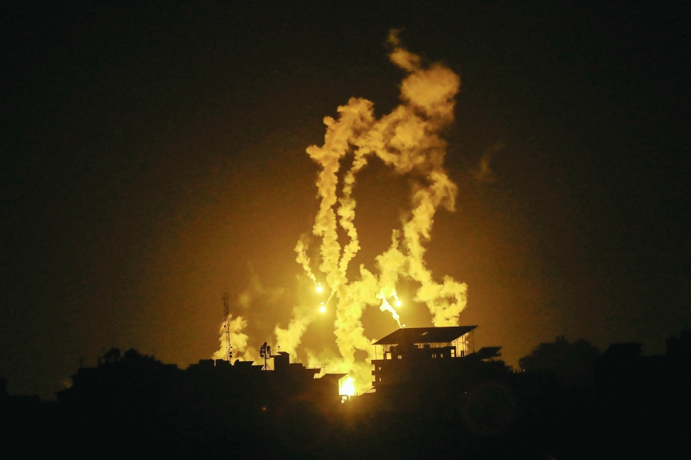 Flares are fired by Israeli forces as smoke rises during Israeli strikes, in Gaza City. — Reuters 