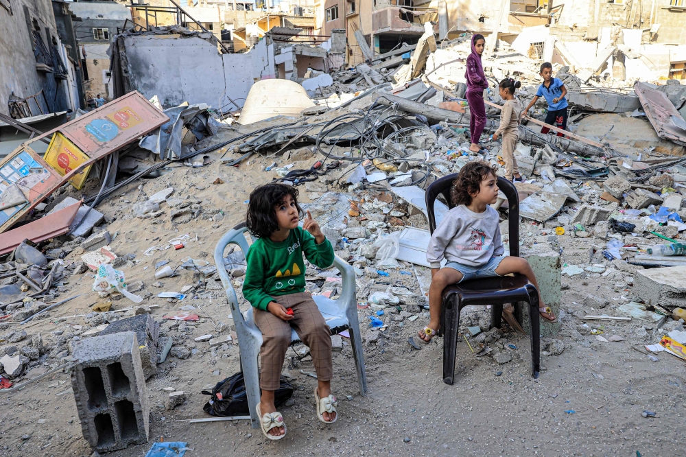 Palestinian children sit in front of the rubble of a destroyed building in Rafah in the southern Gaza Strip
