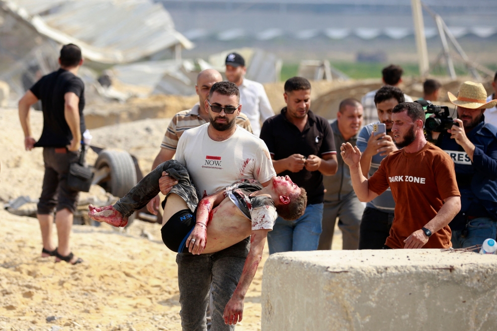 / A man carries away a Palestinian killed in an Israeli airstrike at the Erez crossing