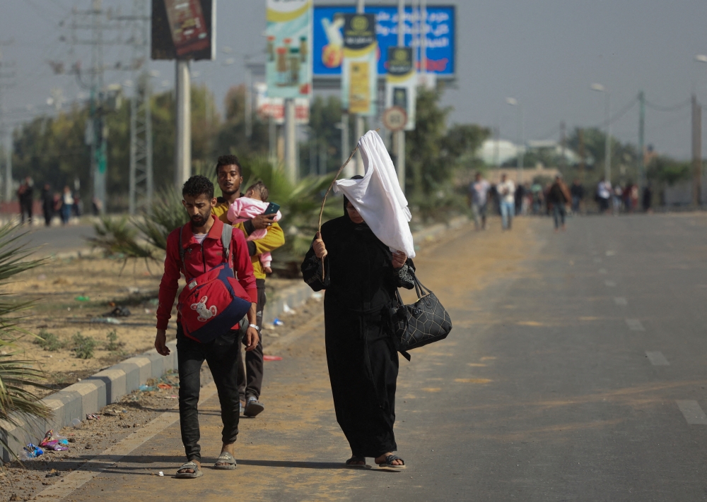 A Palestinian woman holds a white flag while evacuating with a group of civilians from the north of the Gaza 