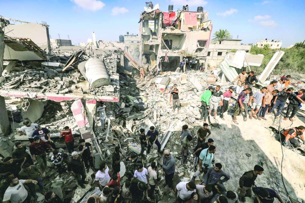 People gather by the rubble of a building that collapsed after Israeli bombardment while searching for survivors and the bodies of victims, in Khan Younis. — AFP