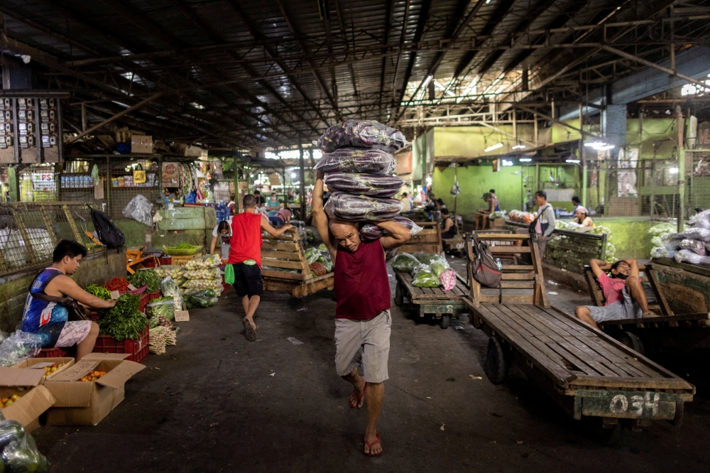 A worker carries vegetables at a market in Quezon City, Metro Manila, Philippines, February 9, 2023. REUTERS