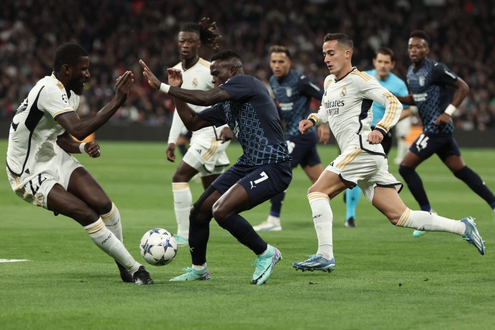 TOPSHOT - Real Madrid's German defender #22 Antonio Rudiger and Real Madrid's Spanish forward #17 Lucas Vazquez (R) vie with Sporting Braga's Portuguese forward #07 Bruma during the UEFA Champions League group C football match between Real Madrid CF and SC Braga at the Santiago Bernabeu stadium in Madrid on November 8, 2023. (Photo by Thomas COEX / AFP)


