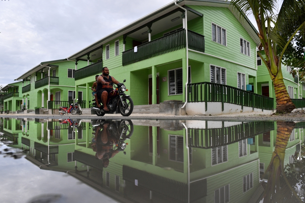 A man riding a motorbike is seen reflected in a puddle of water in Funafuti, Tuvalu.
- Reuters File
