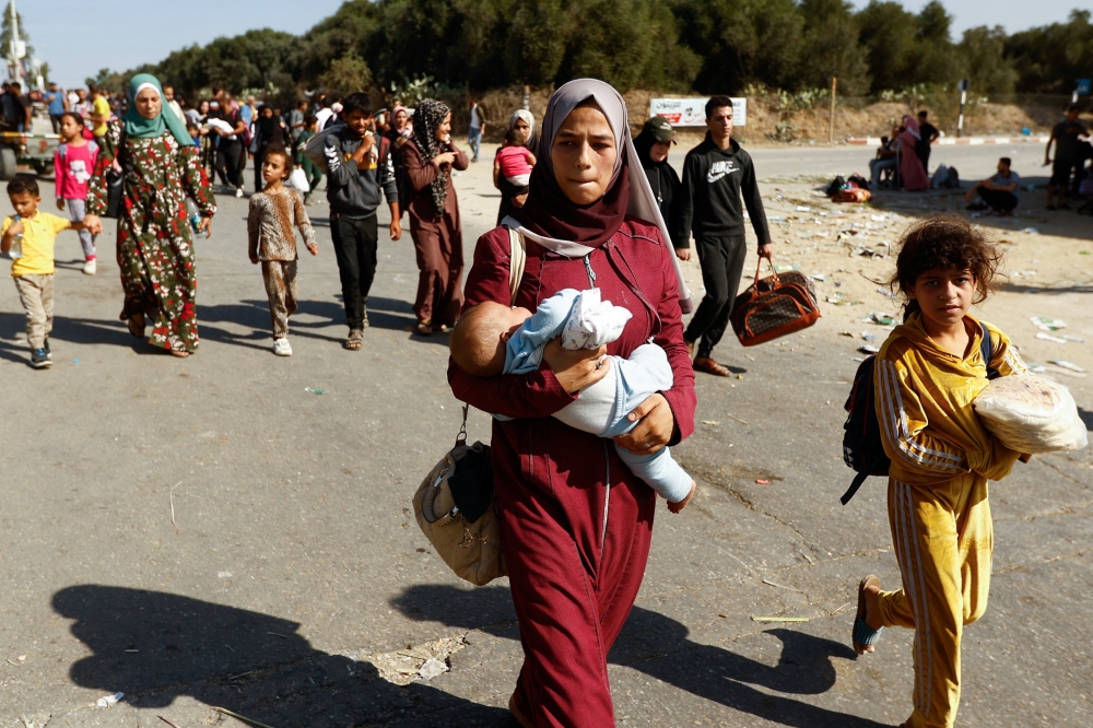 A woman carries a child while Palestinians fleeing north Gaza move southward as Israeli tanks roll deeper into the enclave in the central Gaza Strip on Friday.— Reuters