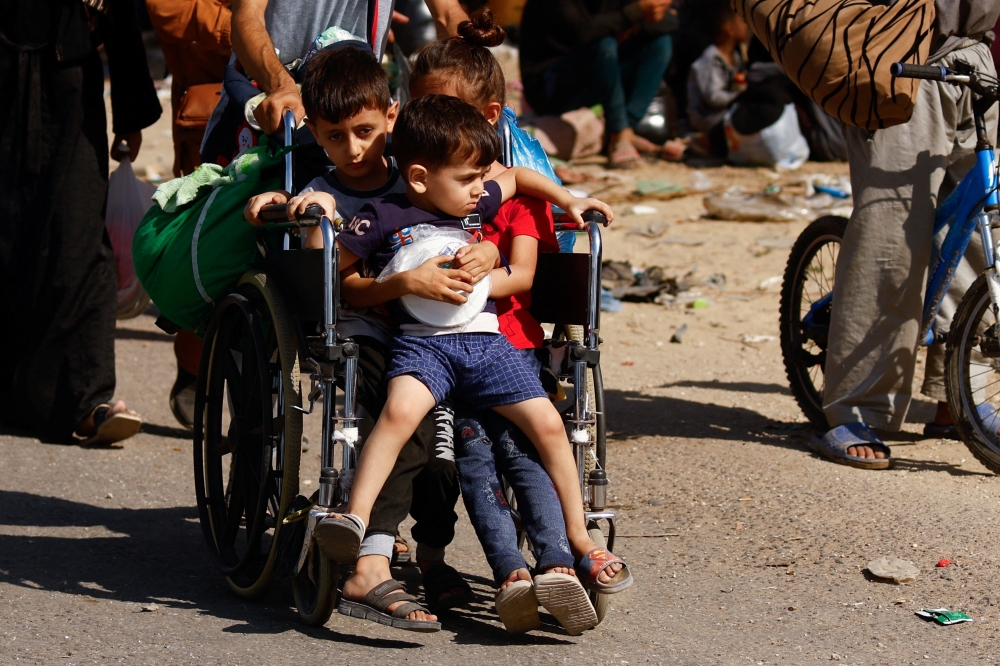 Children ride on a wheelchair while Palestinians fleeing north Gaza 