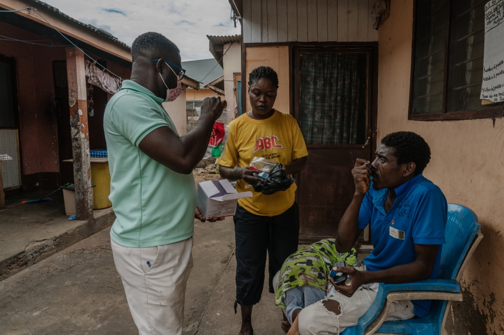 Richard Boadi, left, a nurse at Kaneshie Polyclinic, instructs Sadiya Ribiro and her husband Joshua Dodoo on taking a sample of sputum for tuberculosis testing from the youngest child, in Accra, Ghana, Oct. 24, 2023. (Natalija Gormalova/The New York Times)
