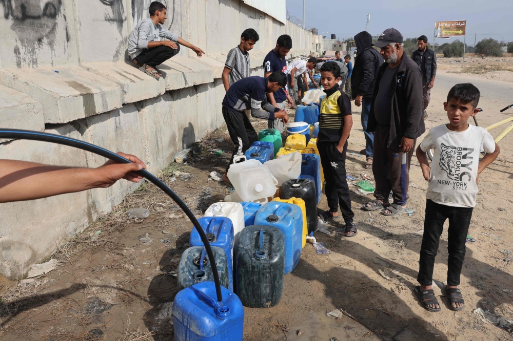 Palestinian children fill containers with water in Rafah, in the southern Gaza Strip. — AFP 