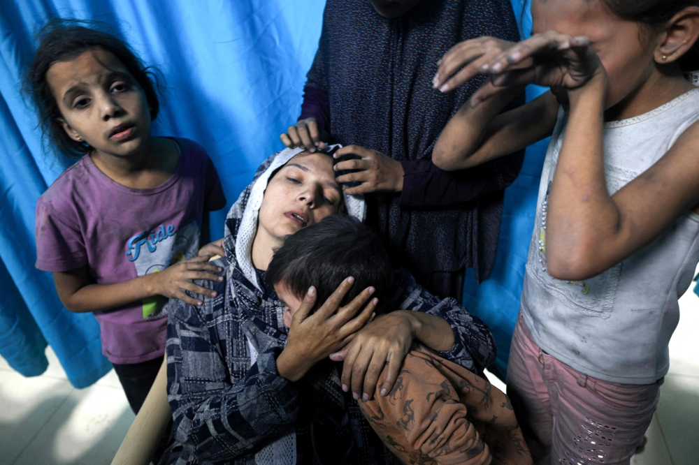  A wounded Palestinian woman from the Baraka family is surrounded by her children upon their arrival at Nasser Hospital in Khan Yunis in the southern Gaza Strip