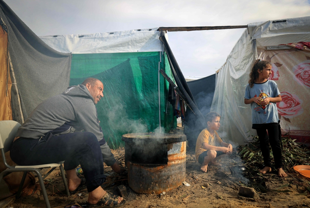 A displaced Palestinian man, who fled from the Israeli bombardment, is now living in a make shift shelter, stocks up an oven outside a tent in Khan Yunis, in the southern Gaza Strip. — AFP