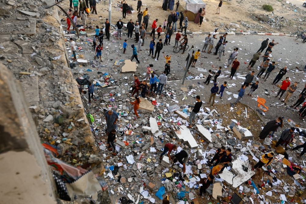 People walk among debris at the site of an Israeli strike on the apartment building, amid the ongoing conflict in Khan Younis in the southern Gaza Strip 