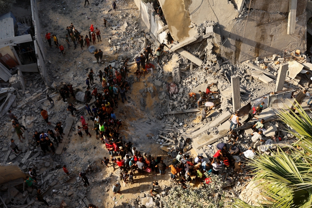 Palestinians gather as others search for casualties at the site of an Israeli strike, in Khan Younis in the southern Gaza Strip. — Reuters 
