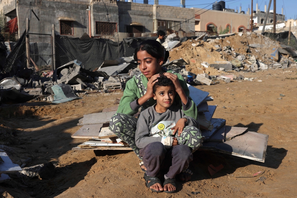 A Palestinian girl and her brother sit amidst the debris of a house following an Israeli strike in Rafah in the southern Gaza Strip. — AFP 
