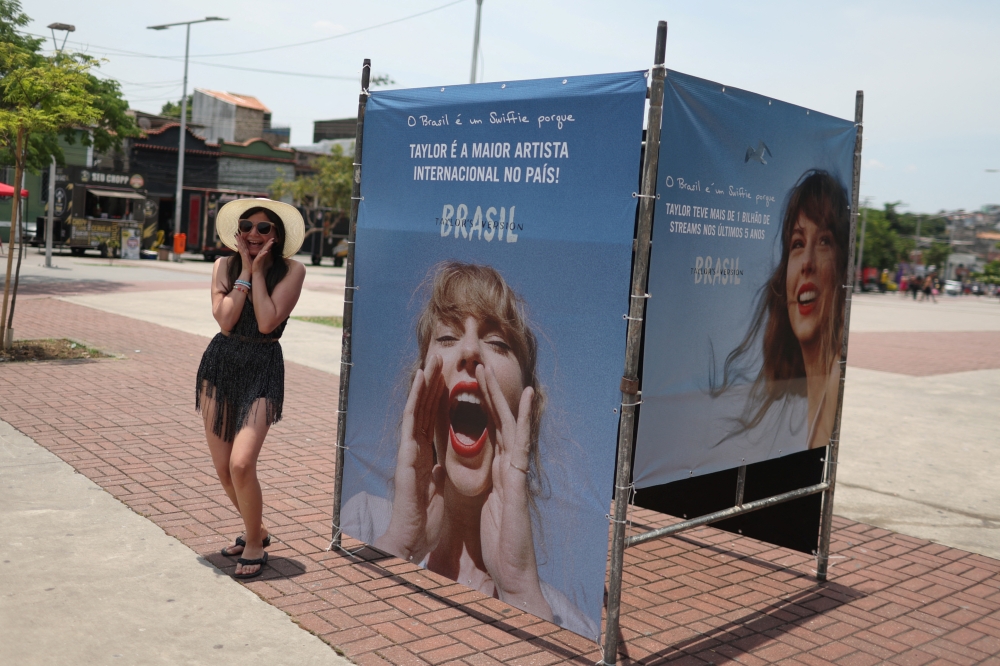 A girl poses next to a photo of singer Taylor Swift, before a concert