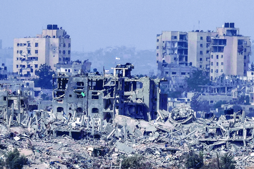 The picture taken from southern Israel shows Israeli flags flying over destroyed buildings inside the Gaza Strip on Sunday. -- AFP