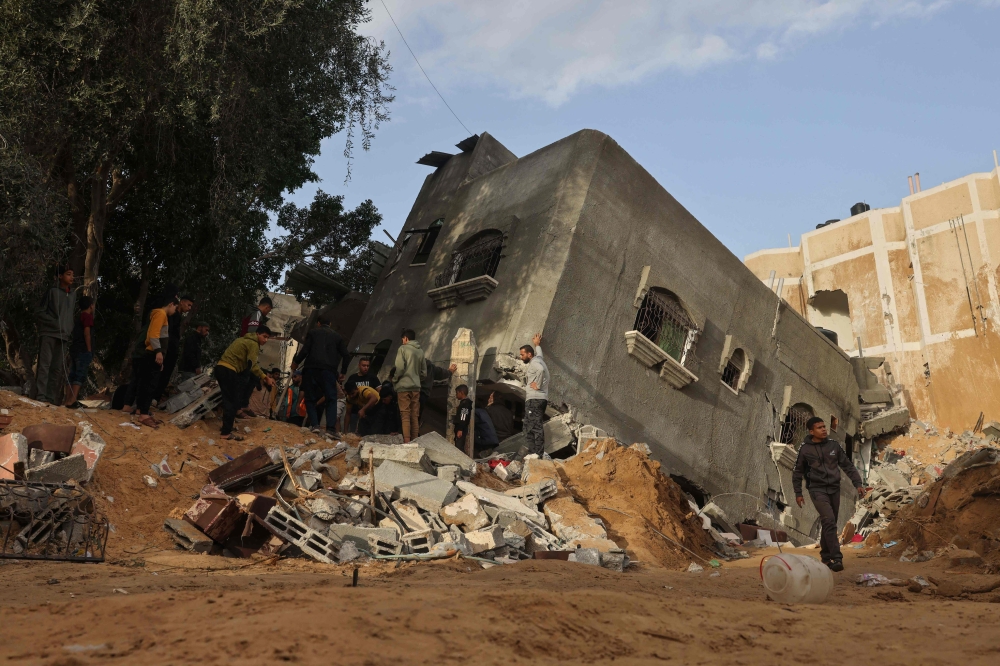 People walk near a house destroyed in an Israeli strike in Rafah in the southern Gaza Strip. — AFP 