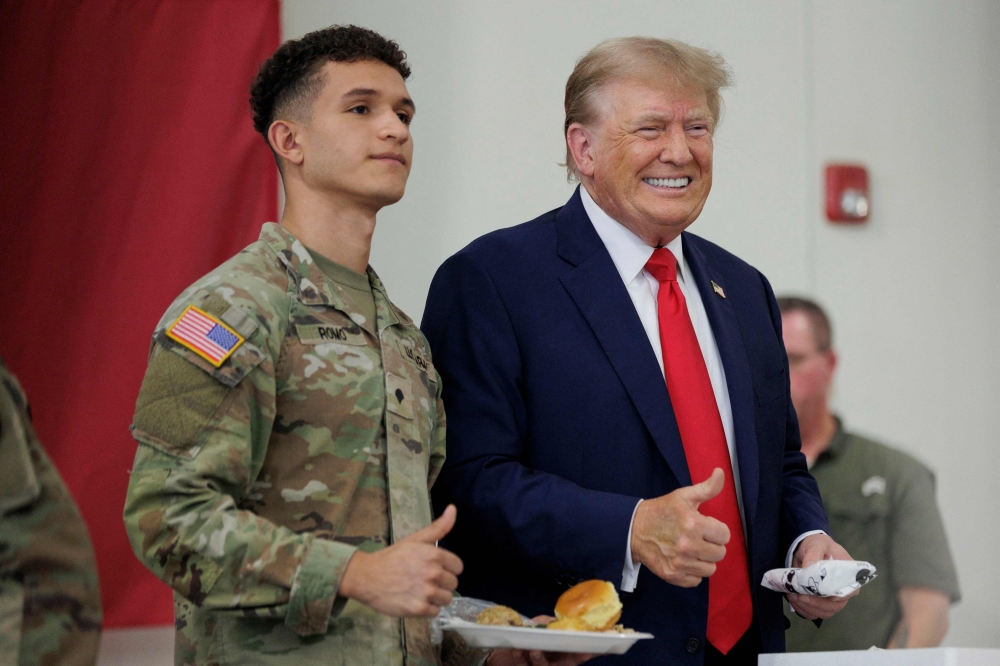 Former US president Donald Trump poses for a photo with a service member at the South Texas International airport on Sunday. - AFP