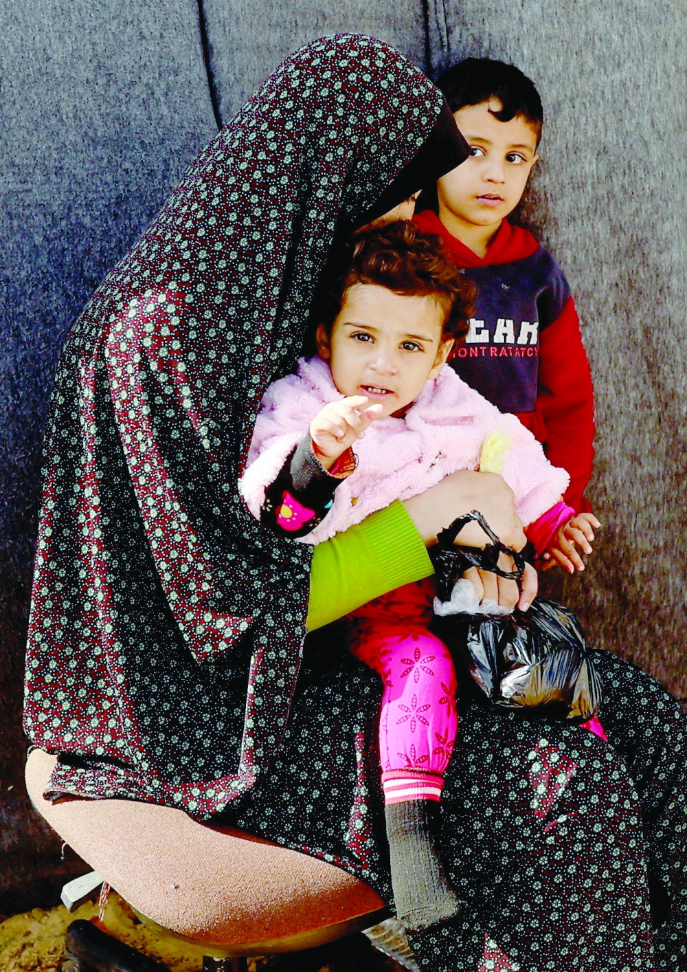 A displaced Palestinian woman sits with children in a tent camp in Khan Younis in the southern Gaza Strip, on Monday. - Reuters