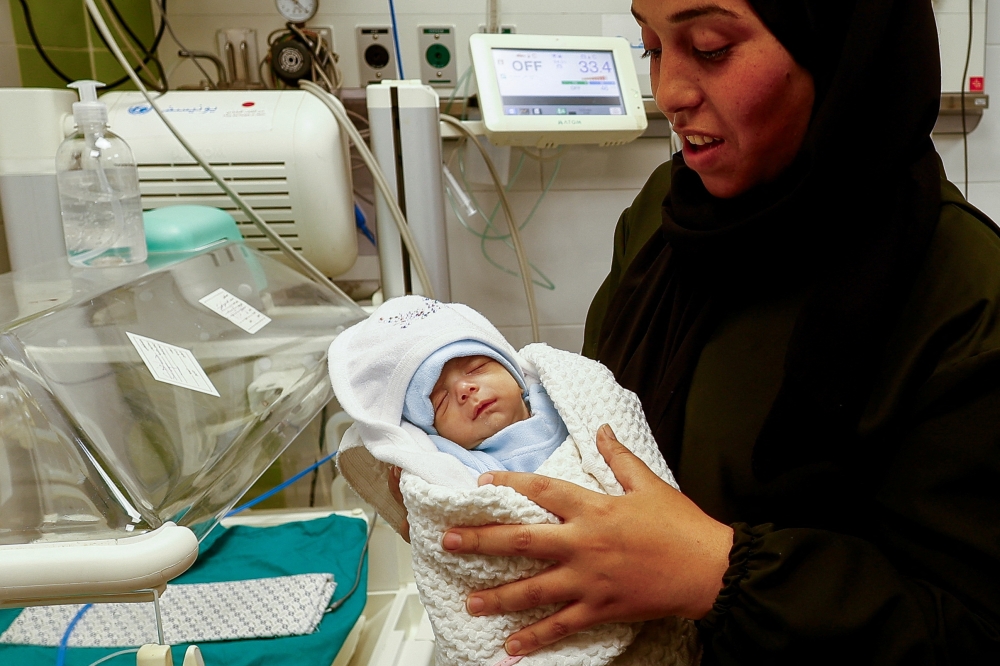 A Palestinian mother holds her newborn Anas Sbeta, who was placed in an incubator after being evacuated from Al Shifa Hospital in Gaza City due to the ongoing Israeli ground operation against the Palestinian Islamist group Hamas, as he is discharged from a hospital in Rafah, southern Gaza Strip, November 21, 2023. REUTERS/Ibraheem Abu Mustafa