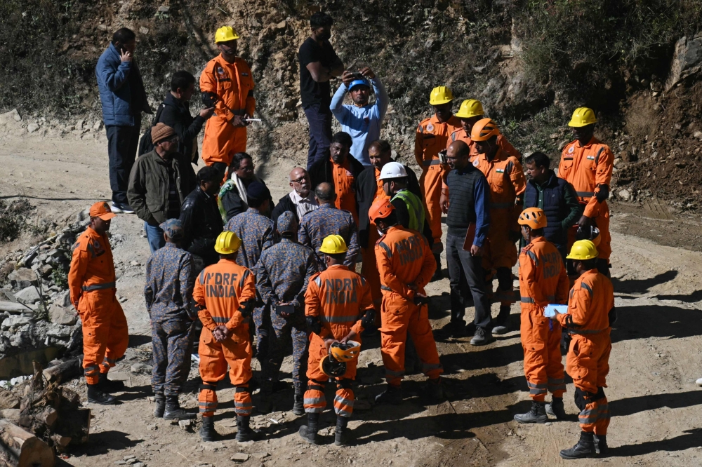 National Disaster Response Force (NDRF) personnel interact with officials during the rescue operation for trapped constructions workers days after a section of the under construction Silkyara road tunnel collapsed in the Uttarkashi district of India's Uttarakhand state. - AFP 
