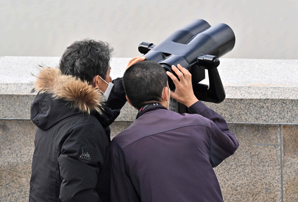 Visitors use binoculars to look at a view of the North Korean side of the Demilitarised Zone dividing the two Koreas from the Odusan Unification Observatory in Paju. - AFP