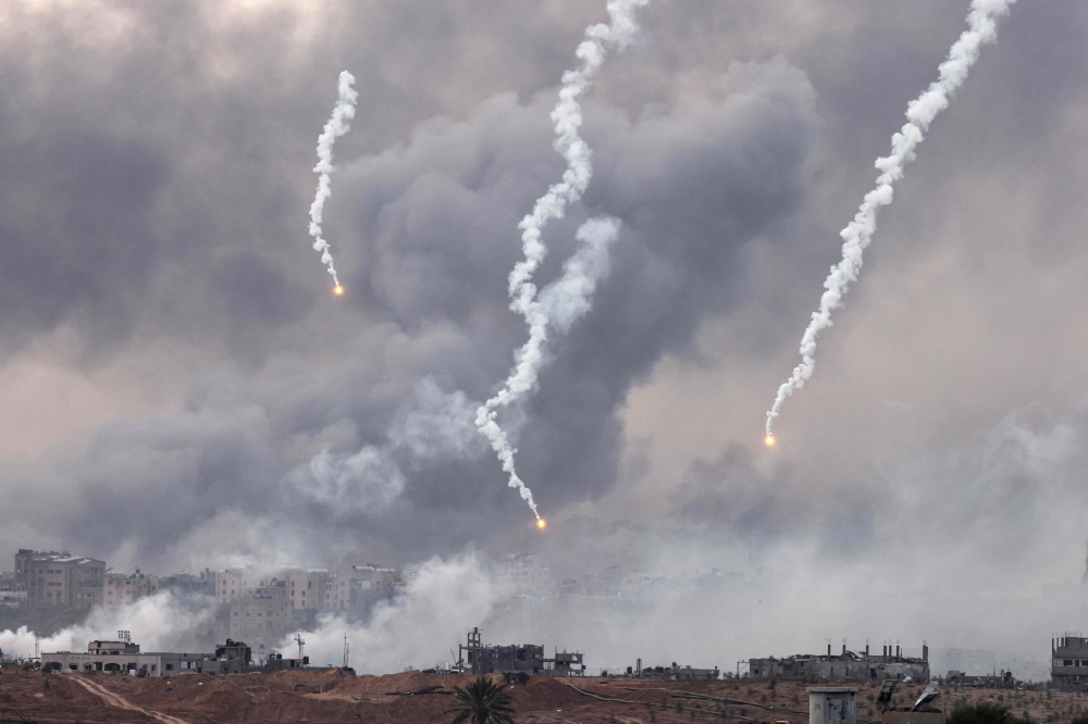 This picture taken from southern Israel near the border with the Gaza Strip shows Israeli flares dropping and smoke billowing over north Gaza amid ongoing battles between Israel and the Hamas movement. - AFP