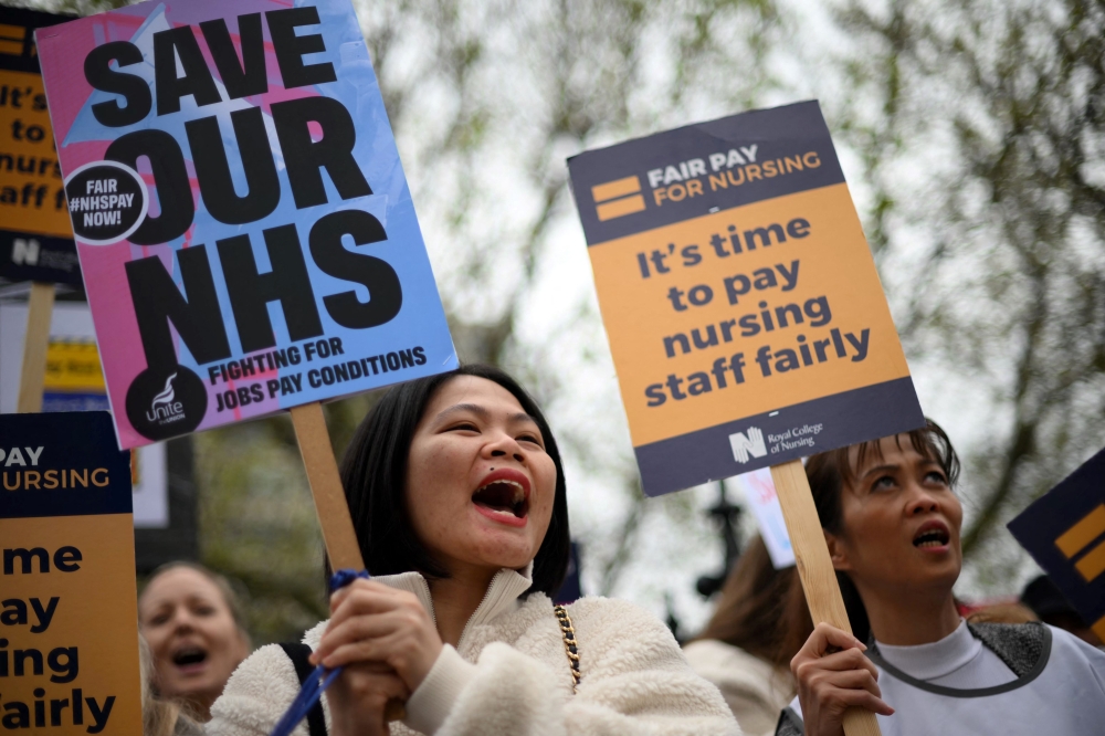 Healthcare workers hold placards as they demonstrate on Westminster Bridge, near to St Thomas' Hospital in London as members of Unite and the Royal College of Nursing (RCN) continue their industrial action. - AFP File 