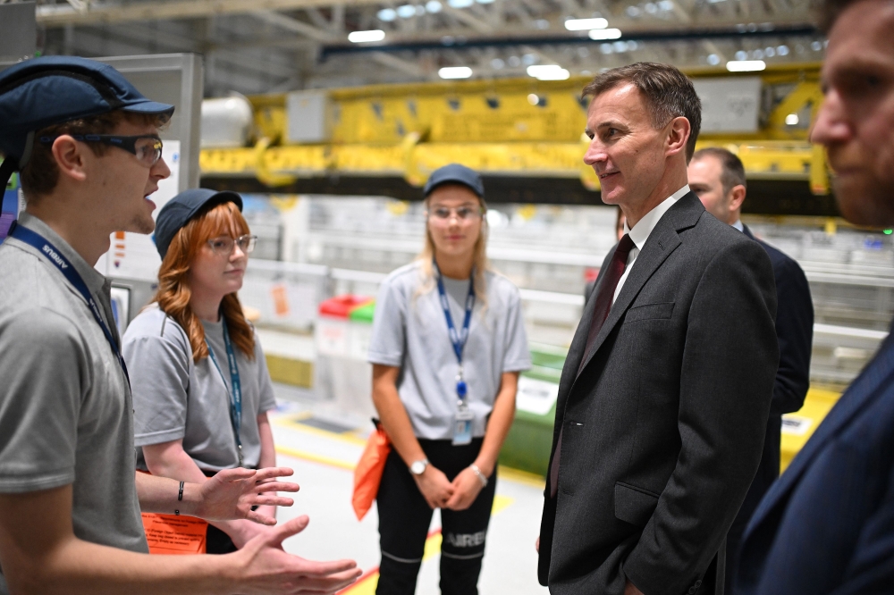 Britain's Chancellor of the Exchequer Jeremy Hunt reacts as he meets apprentices, on the Airbus A350 wing manufacturing productinon line, during a visit to the Airbus Broughton plant in north Wales. - AFP


