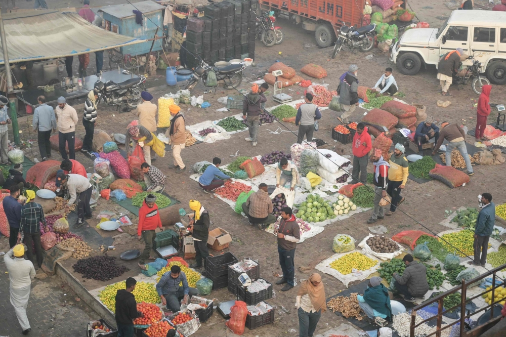 Vendors sell vegetables at a wholesale market amid dense smog in Amritsar