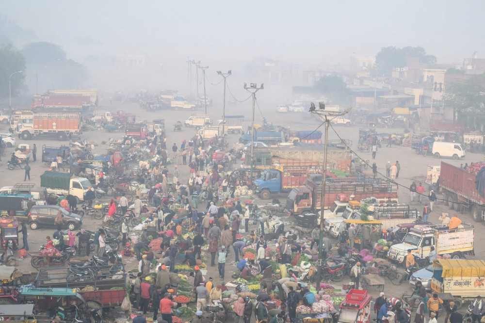 People gather at a wholesale vegetable market amid dense smog 