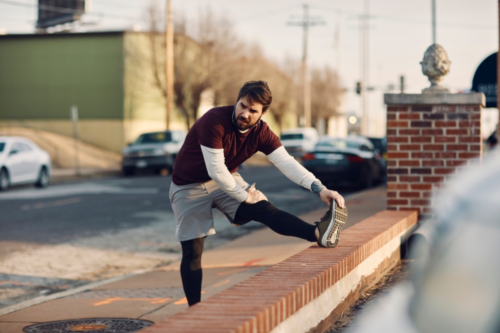Young,Caucasian,Man,Stretching,Before,Jogging,And,Exercising,On,A