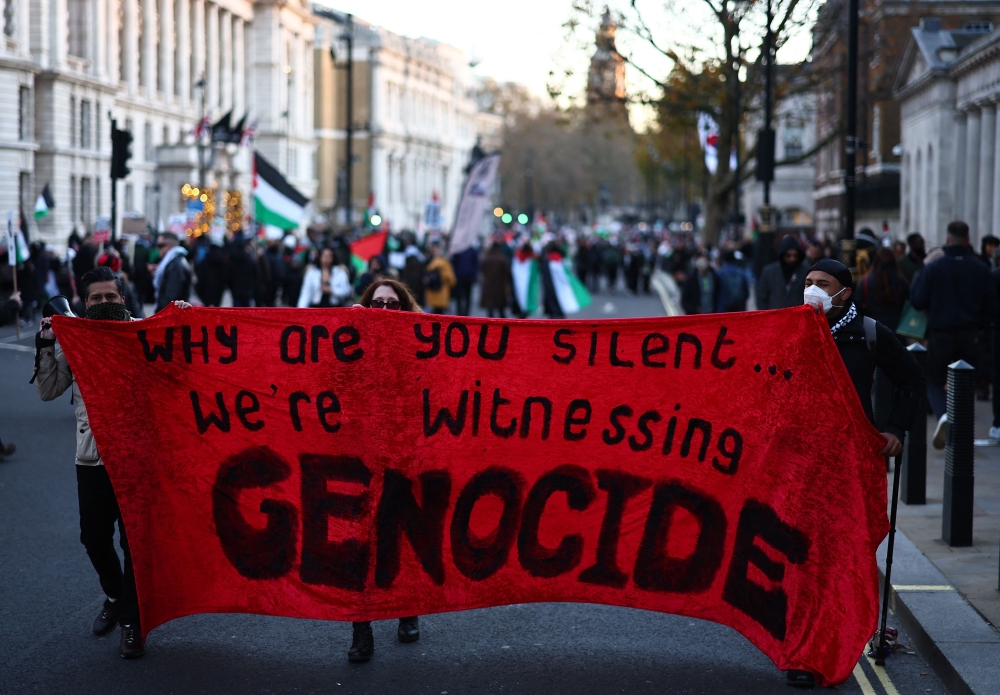 Protesters hold a banner in as they take part in a 'National March For Palestine' in central London. — AFP 