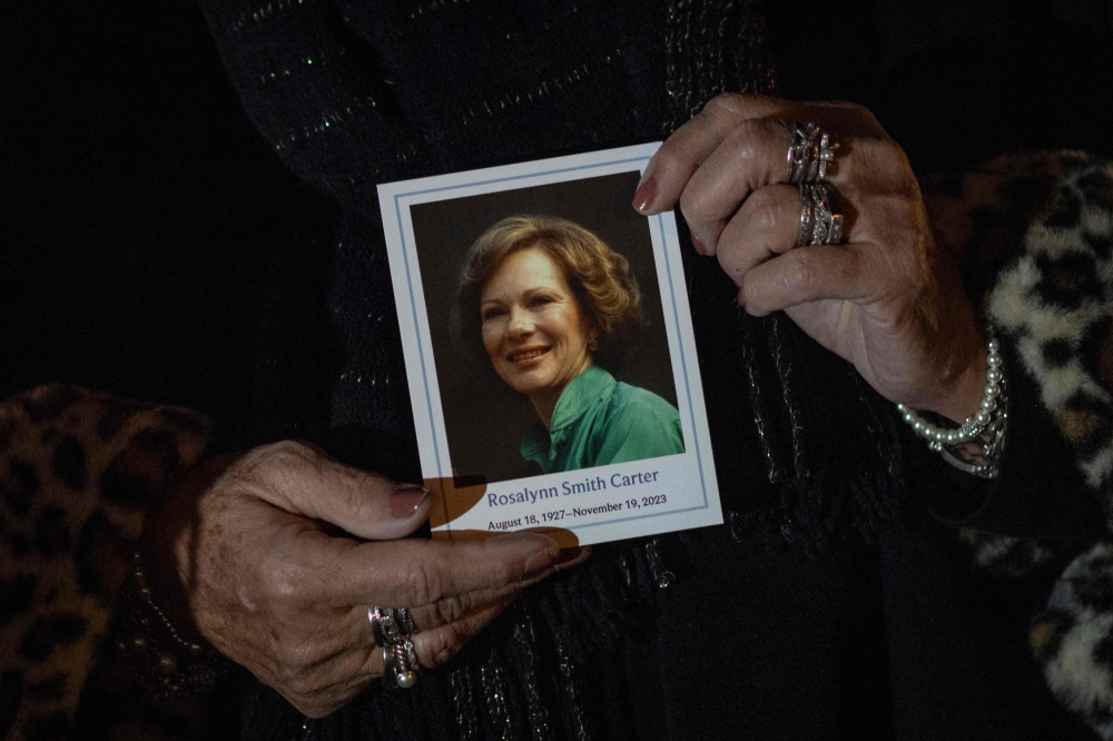 A woman holds a photo of former US First Lady Rosalynn Carter as her body lays in repose at the Carter Presidential Library in Atlanta, Georgia