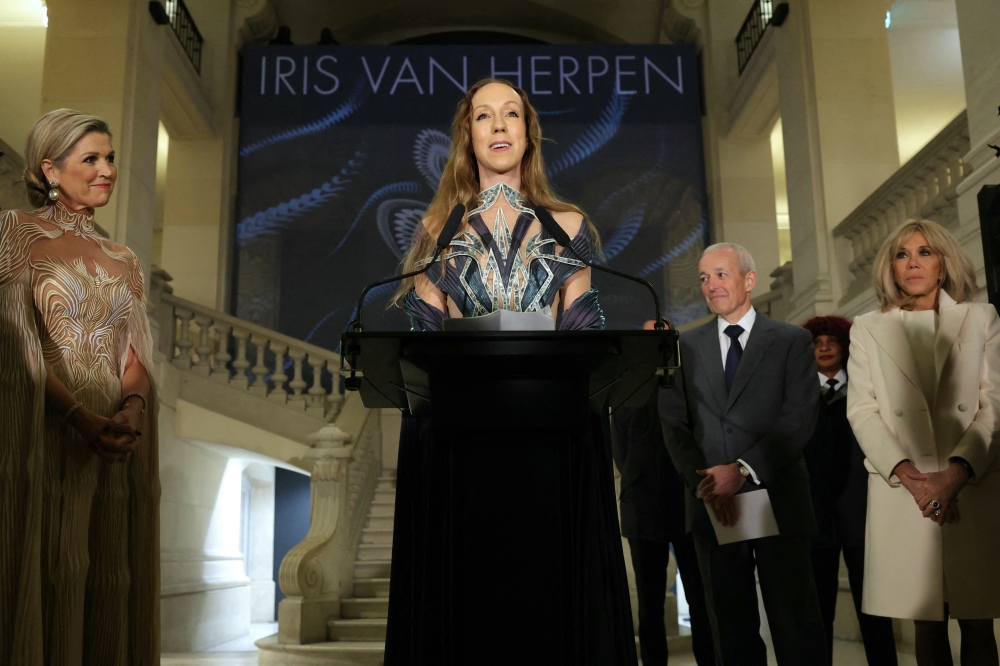 Dutch fashion designer Iris van Herpen (C) speaks during the opening of her exhibition 'Iris van Herpen: Sculpting the Senses' in the presence of Queen Maxima of the Netherlands (L) and wife of the French President Brigitte Macron (R) at the Musee des Arts Decoratifs, in Paris, on November 28, 2023. The exhibition, inaugurated on November 28, 2023 by Queen Maxima of the Netherlands and Brigitte Macron opens to the general public on Novemeber 29, 2023 and features 100 haute couture dresses by the Dutch couturier. (Photo by Thomas SAMSON / AFP)

