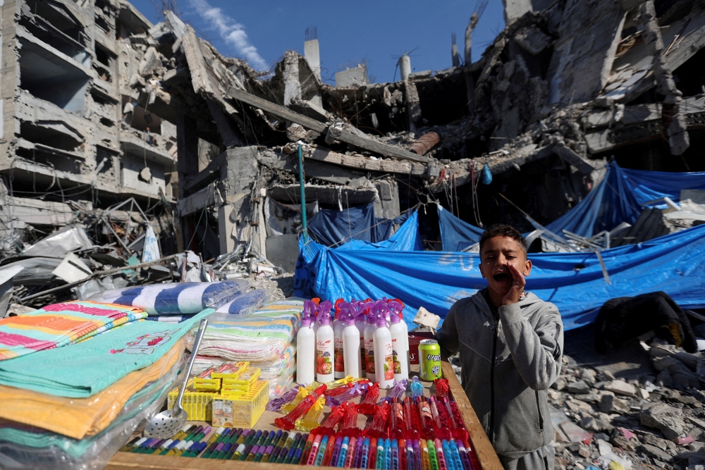 A Palestinian vendor offers his products in an open-air market near the ruins of houses and buildings destroyed in Israeli strikes during the conflict, amid a temporary truce between Hamas and Israel, in Nuseirat refugee camp in the central Gaza Strip on Thursday. — Reuters