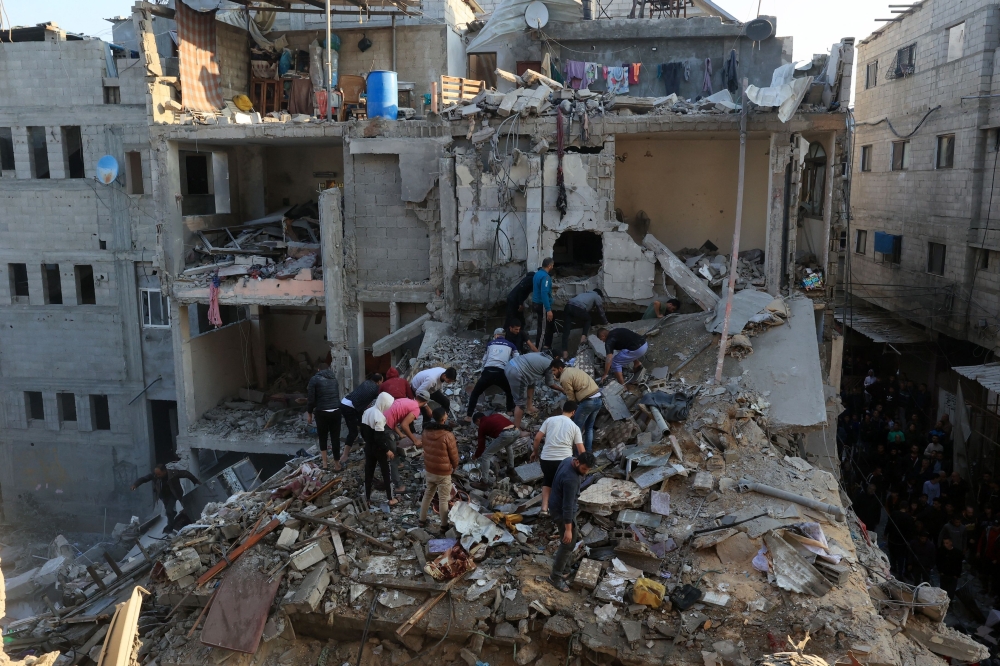 Palestinians inspect the destruction around residential buildings following Israeli air strikes in the Rafah 