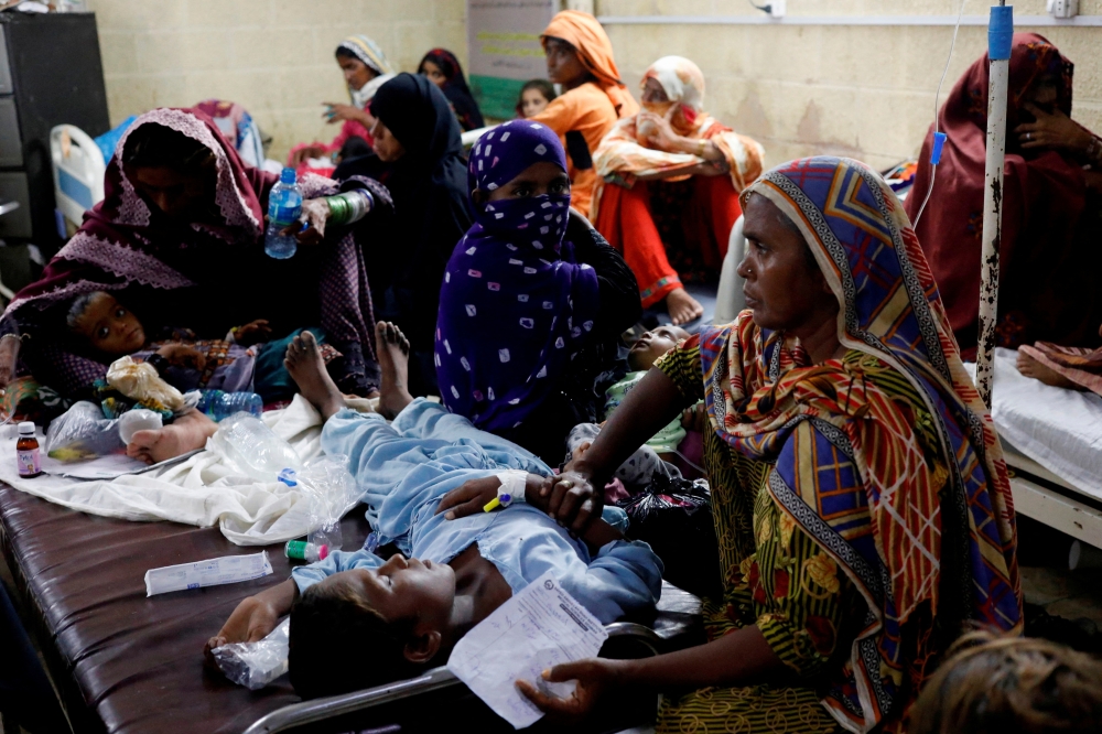 Women affected by the floods sit with their children suffering from malaria and fever