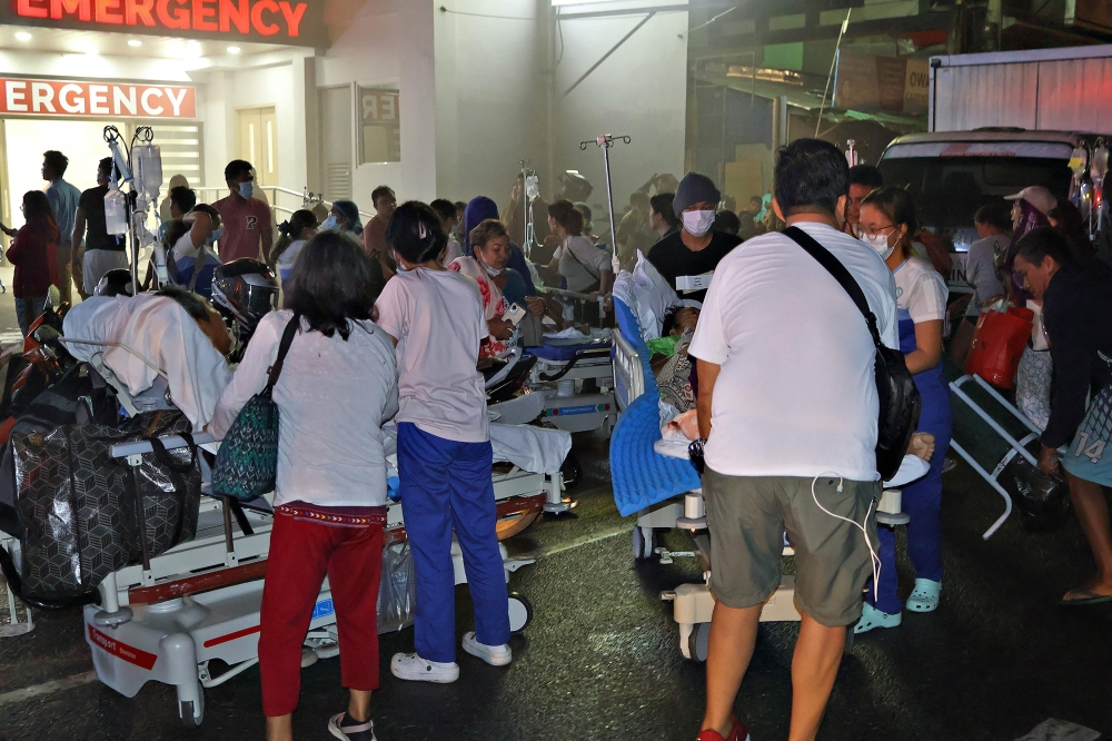 Residents and medical personnel evacuate patients from inside a hospital after a 7.6 earthequake 