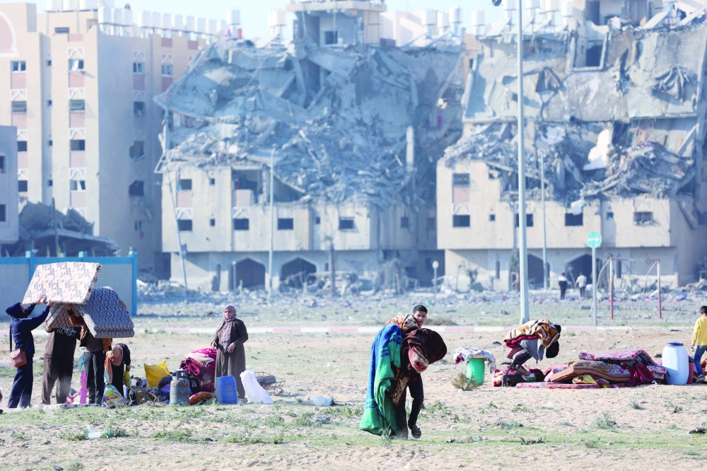 Palestinians carry their belongings following Israeli strikes on residential buildings, in Khan Younis in the southern Gaza Strip. — Reuters 
