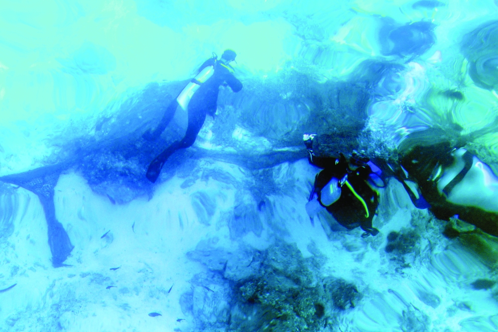 Volunteer divers remove fishing nets from coral reefs at Oman's Daymaniyat Islands.  — AFP