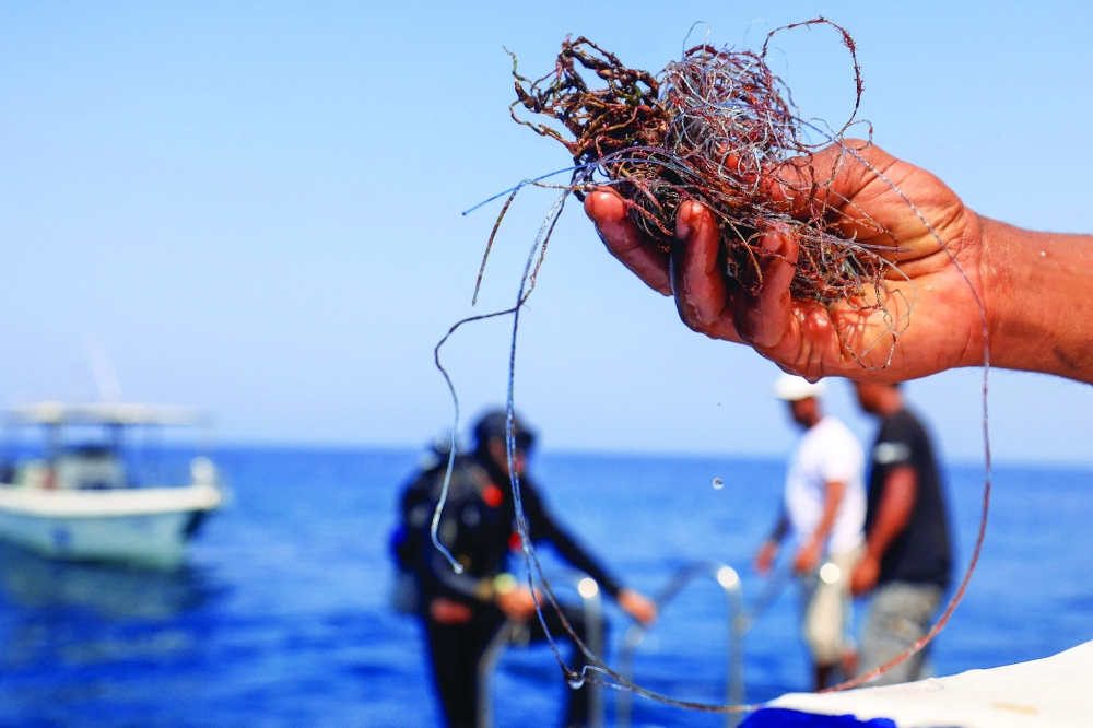 A volunteer diver shows fishing nets removed from coral reefs at Oman's Daymaniyat Islands. — AFP