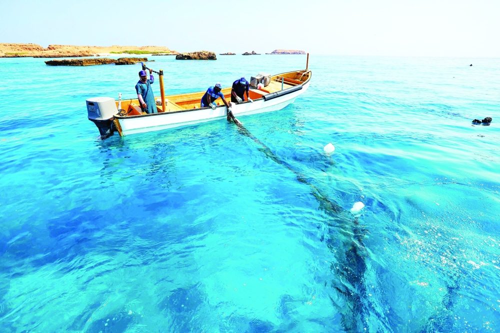 Volunteers pull discarded fishing nets removed by divers from coral reefs at Daymaniyat Islands. — AFP