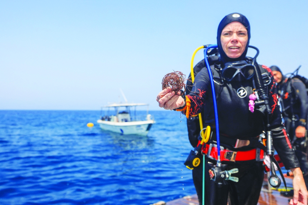 A volunteer diver shows fishing nets removed from coral reefs at Daymaniyat Islands. — AFP
