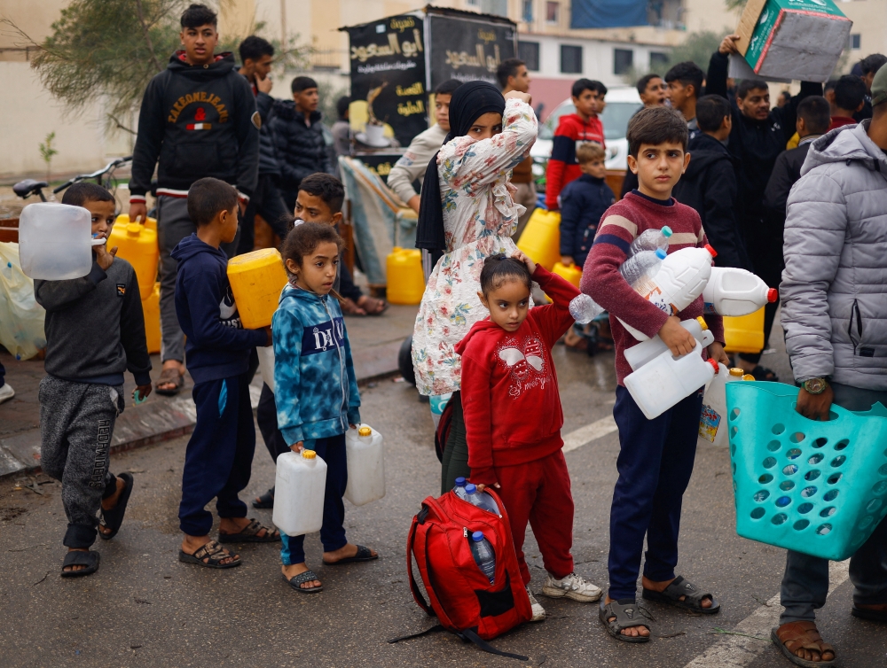 Palestinian children queue to collect water amid water shortages during the ongoing conflict between Israel and Palestinian Islamist group Hamas, in Rafah in the southern Gaza Strip, December 5, 2023. REUTERS/Mohammed Salem
