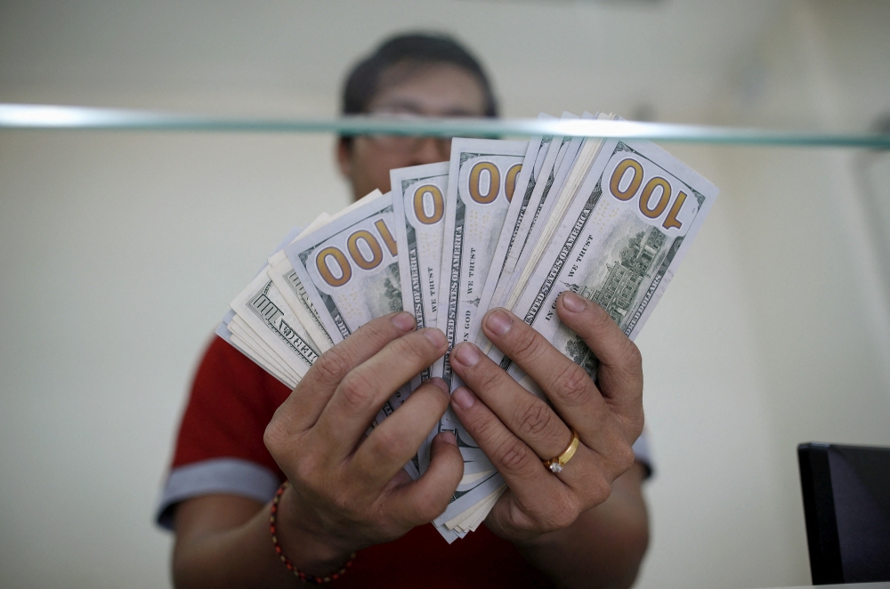 FILE PHOTO: Bank staff shows U.S. hundred dollars bills at AYA Bank's money changer in Yangon