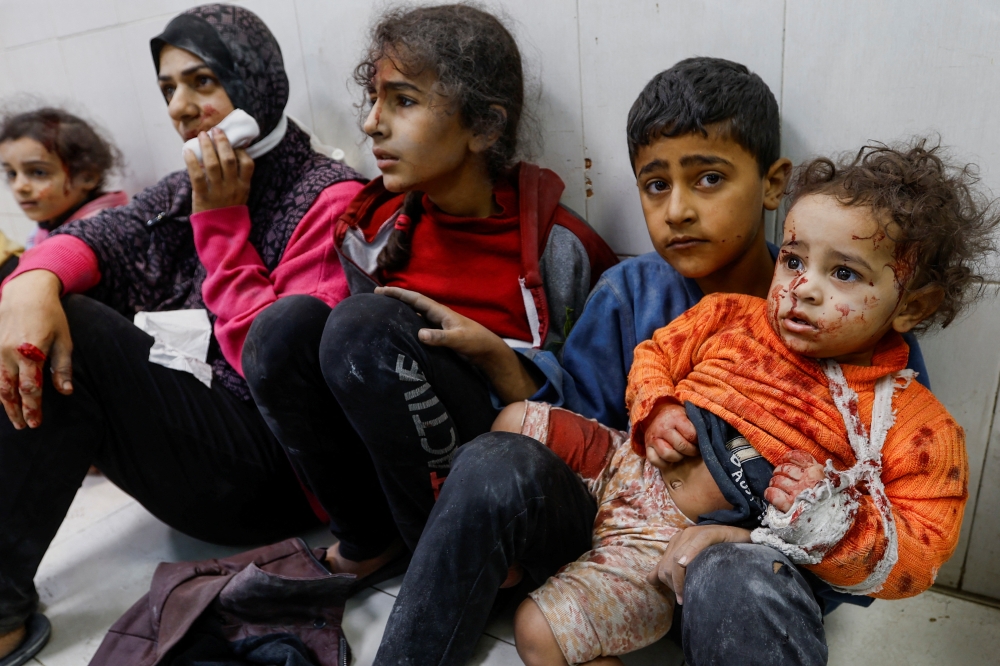 Wounded Palestinians sit on the floor at Nasser hospital following Israeli strikes