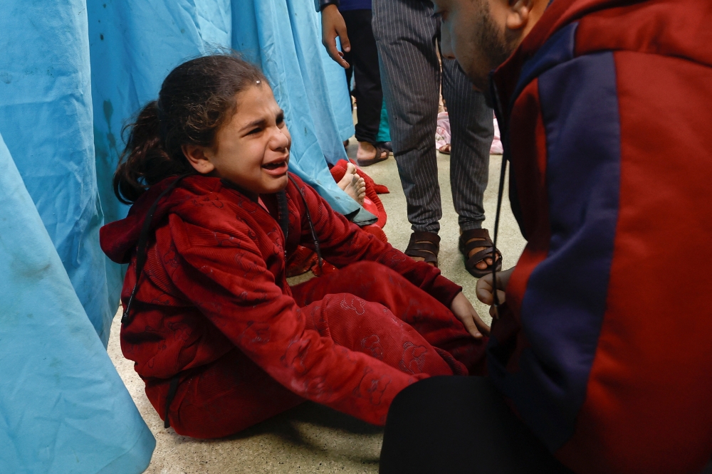 A wounded Palestinian child sits on the floor of Nasser hospital