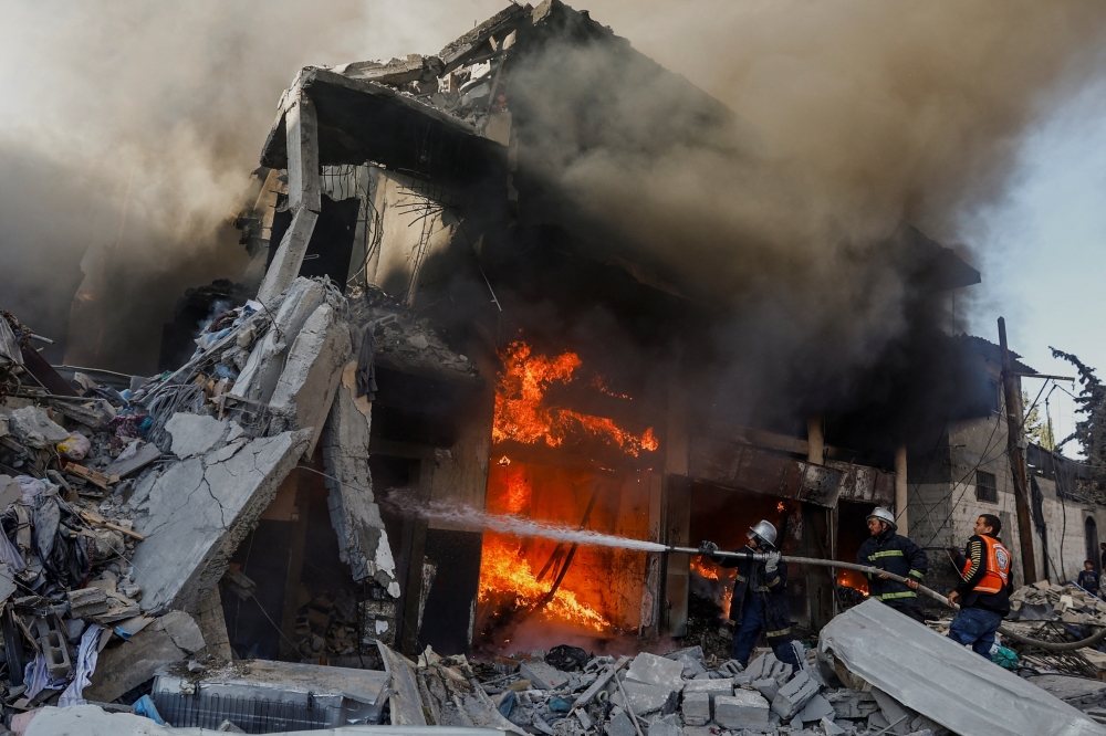 Palestinian firefighters work to extinguish a fire in a house after an Israeli strike