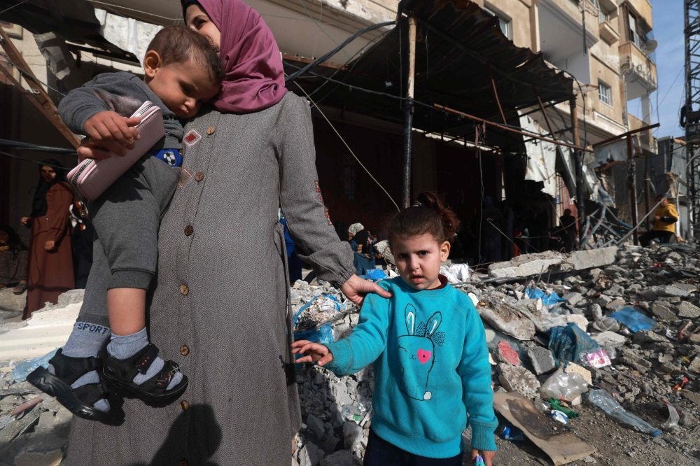 Members of a displaced Palestinian family stand amid the rubble in Rafah on a street in the southern Gaza Strip 
